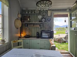 a kitchen with green cabinets and a table and a window at Hammergaarden Stabbursstua - Heritage Loft Stay in Sortland