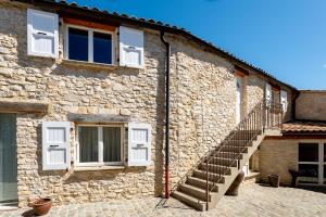 a stone building with white windows and a staircase at La Ferme D'estafinette in Redortiers