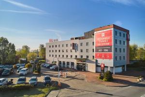 a large building with cars parked in a parking lot at Ibis Częstochowa in Częstochowa