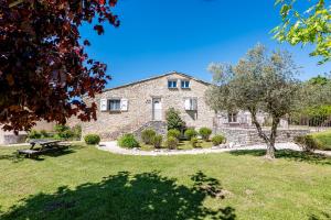 a stone house with a picnic table in the yard at Mas des Oliviers in Redortiers
