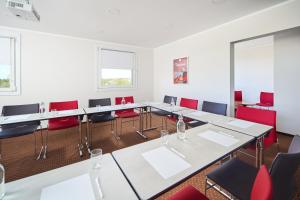 a conference room with white tables and red chairs at Ibis Częstochowa in Częstochowa