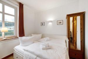 a white bed in a room with a window at Gut Rattelvitz, Parterre A OST in Gingst