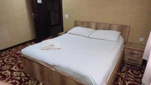 a bedroom with a large bed with two towels on it at Sitora in Chirchiq