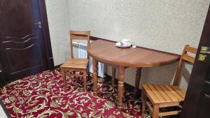 a wooden table with two chairs and a cup on it at Sitora in Chirchiq