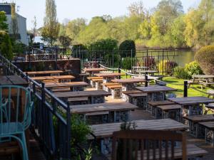 a row of wooden tables and benches next to a lake at Diglis House Hotel in Worcester +78 photos