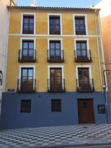 un edificio giallo e blu con finestre e balconi di Apartamentos Viejo Continente a Cuenca