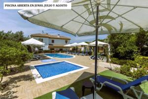 a pool with chairs and an umbrella in front of a house at Hostal y Apartamento Rural Los Naranjos in Melegis