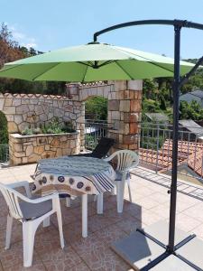 a table and chairs and an umbrella on a patio at Apartman Jure in Jablanac +16 photos