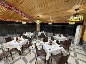 a dining room with white tables and chairs and chandeliers at Golden Emir Residence in Bukhara