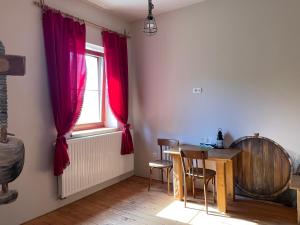 a dining room with a table and a window with red curtains at Vamiš in Gornji Petrovci +24 photos