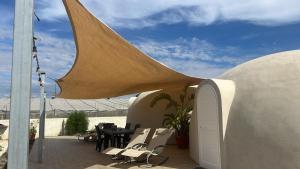 a patio with tables and chairs and a umbrella at Nausicaa Guesthouse in Marsala