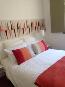 um quarto com uma cama branca e almofadas coloridas em Appartement Maison Aubanel em Avignon