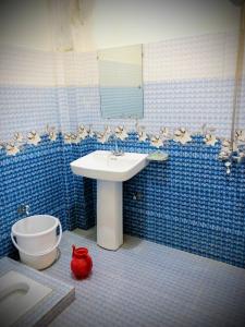 a blue tiled bathroom with a sink and a toilet at Rayn Basayra Kashmir in Bāta