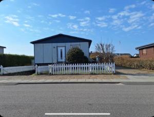 a small house with a white fence next to a street at Cozy Apartment in Hirtshals in Hirtshals