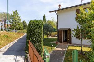 a fence next to a white house with a hedge at Bc Garda House in Peschiera del Garda
