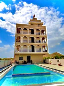 a building with a swimming pool in front of a building at Geetanjali hotel and resort in Udaipur