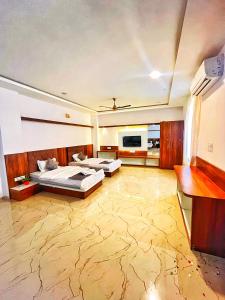 a large room with two beds and a television at Geetanjali hotel and resort in Udaipur