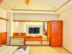 a bedroom with a television and a wooden cabinet at Geetanjali hotel and resort in Udaipur