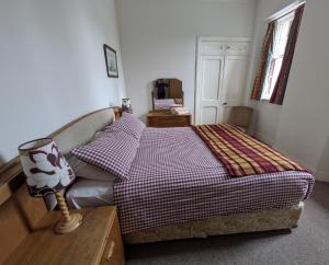 a bedroom with a bed with a checkered blanket at Strathpeffer Holiday Cottages in Strathpeffer
