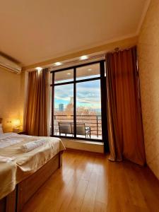 a bedroom with a bed and a large window at Hotel Vera View in Tbilisi City