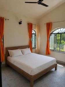a bedroom with a bed and two windows at Jairam Eco Villa in Bāruipur