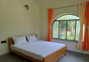 a bedroom with a bed and a large window at Jairam Eco Villa in Bāruipur
