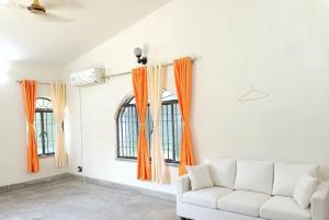 a living room with orange curtains and a couch at Jairam Eco Villa in Bāruipur