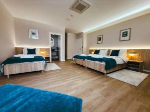 two beds in a hotel room with wood floors at Tiona in Nova Gradiška