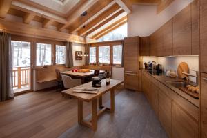 eine Küche mit Holzwänden, einem Tisch und einer Theke in der Unterkunft Chalet Banja in Zermatt