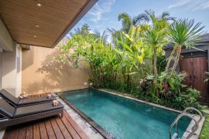a swimming pool in a garden with a wooden deck at Kamajaya Villas in Ubud