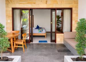a room with a table and a bed and a table and chairs at The Haven in Gili Trawangan