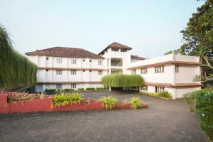a large white building with plants in a courtyard at Clay House in Trichūr