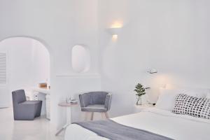 Un dormitorio blanco con una cama y una silla. en Cliff Side Suites, en Firostefani