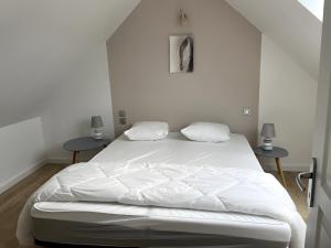 a white bed in a room with two tables at Gite Baie 3km plages in Telgruc-sur-Mer