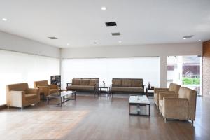 a living room with couches and tables and windows at Clay House in Trichūr