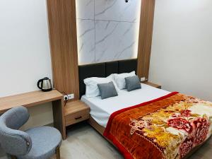 a bedroom with a bed and a desk and a chair at Hotel Rajasthan Inn in Behror