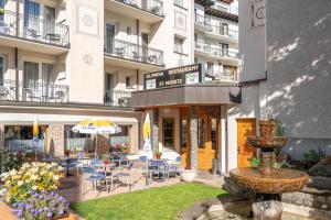 a hotel with a courtyard with chairs and an umbrella at Hotel Bären in St. Moritz