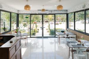 a restaurant with tables and chairs and large windows at The Princess Beachfront Resort in Ban Tha Fat