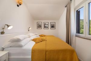 a white bedroom with a bed with a yellow blanket at Apartments Maja in Baška +44 photos