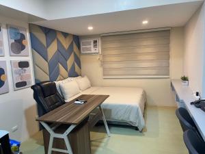 a small room with a bed and a desk and a table at Comfy condo convenient location in Iloilo City