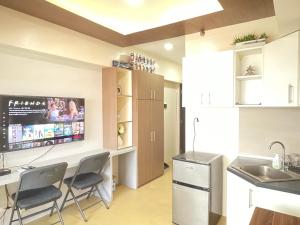 a kitchen with chairs and a sink and a tv at Comfy condo convenient location in Iloilo City