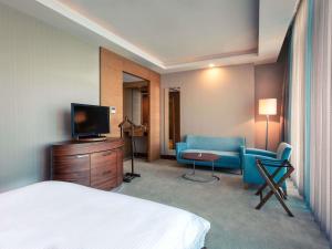 a hotel room with a bed and a tv and a couch at Mercure Istanbul Umraniye in Istanbul