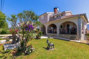 a house with a statue of a dog in the yard at Apartman Mely in Nova Vas