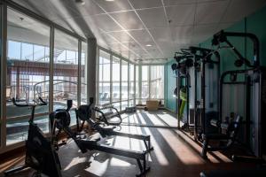 a gym with several tread machines in a room with windows at Selma Spa in Sunne