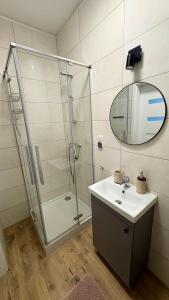 a bathroom with a shower and a sink and a mirror at Apartament Wichrowy in Rowy