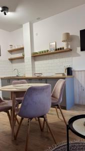 a kitchen with a table and two purple chairs at Apartament Wichrowy in Rowy +6 photos