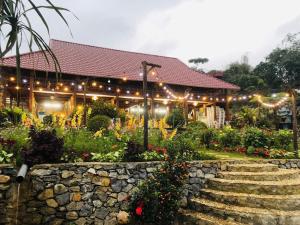 a building with lights and a garden with flowers at Mây farmstay in Ðà Bắc