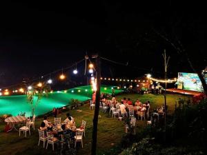 a group of people sitting at tables at a party at night at Mây farmstay in Ðà Bắc