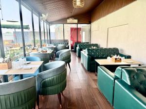 a restaurant with green seats and tables and windows at Hotel Lotus castle in Bathinda