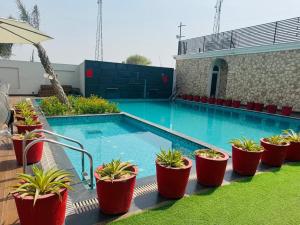 a swimming pool with potted plants next to a building at Hotel Lotus castle in Bathinda +2 photos